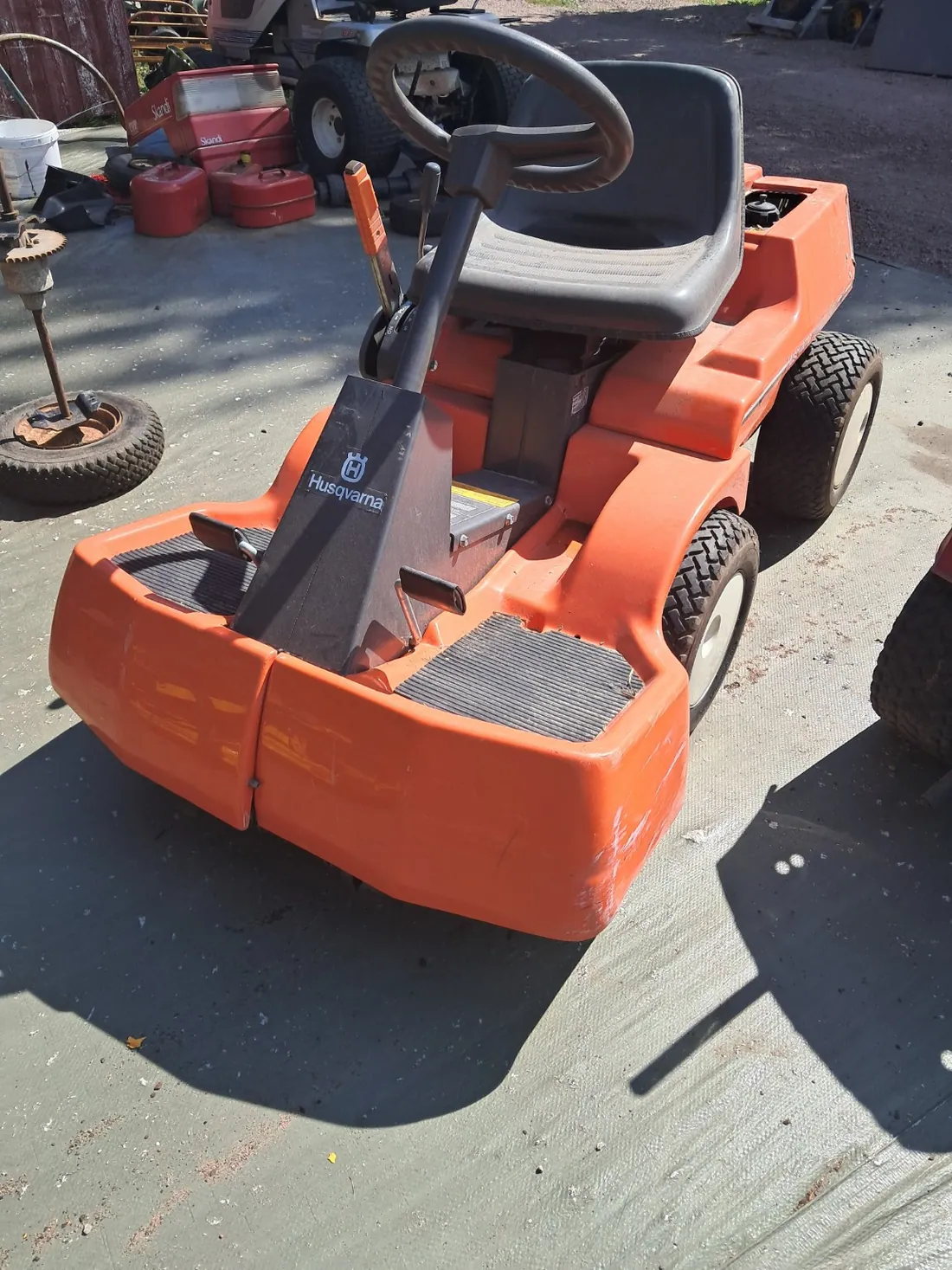Äldre orange Husqvarna åkgräsklippare på betongunderlag